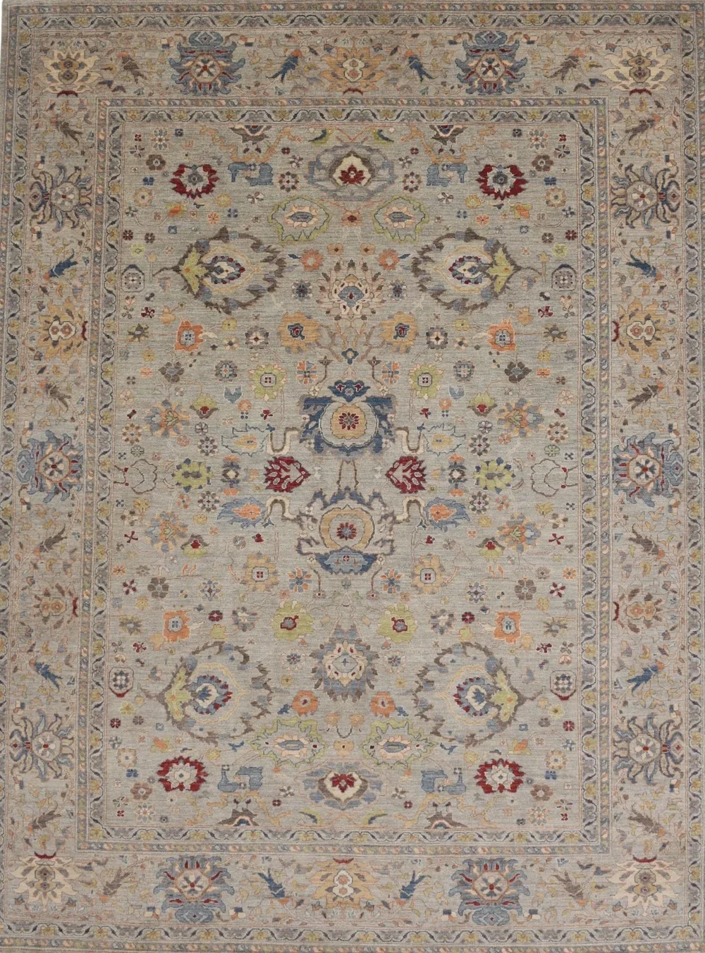 Detailed patterned area rug with floral and geometric motifs in shades of beige, red, blue, green, and orange.