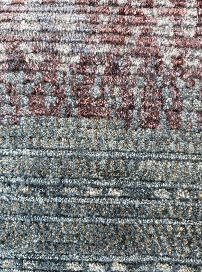 Close-up of a textured fabric surface with multicolored yarns and embroidered red and purple text.