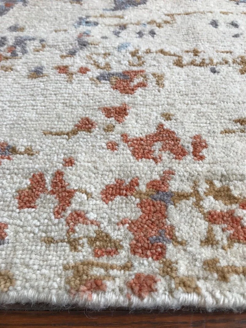 Close-up of a decorative area rug with abstract pattern in cream, red, brown, and gray colors.