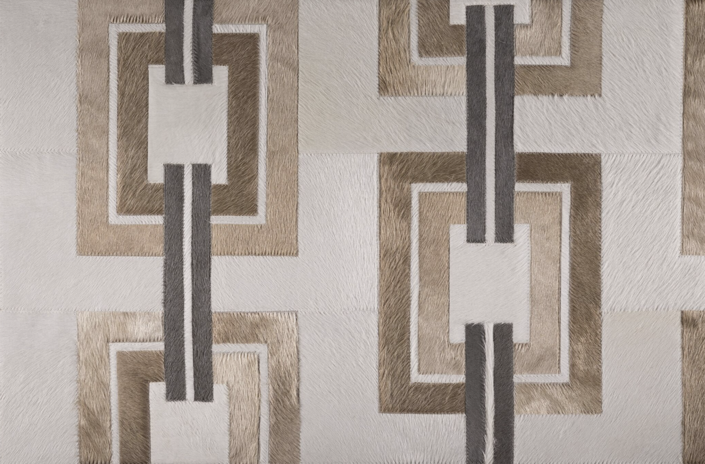 A patterned textile with geometric shapes in shades of beige, brown, gray, and white, featuring rectangular and parallel line designs.