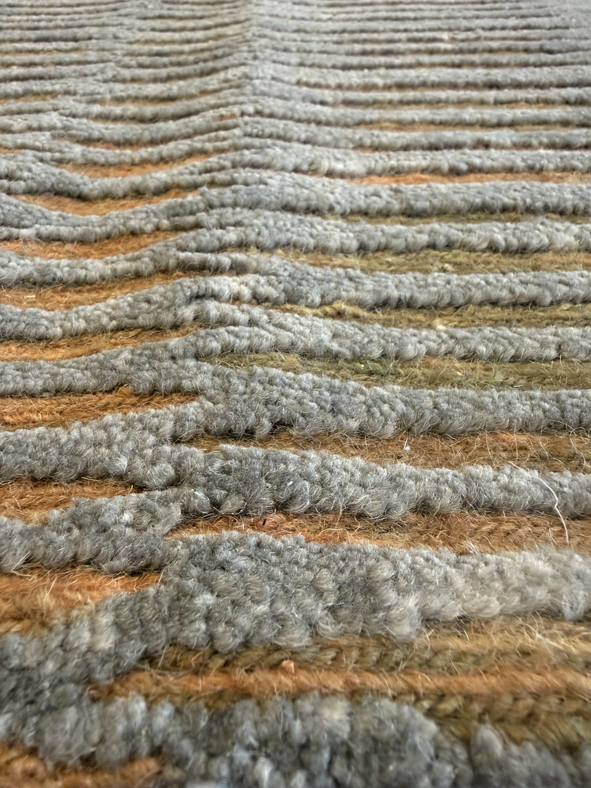Close-up of a textured, grey rug with a amber stripes