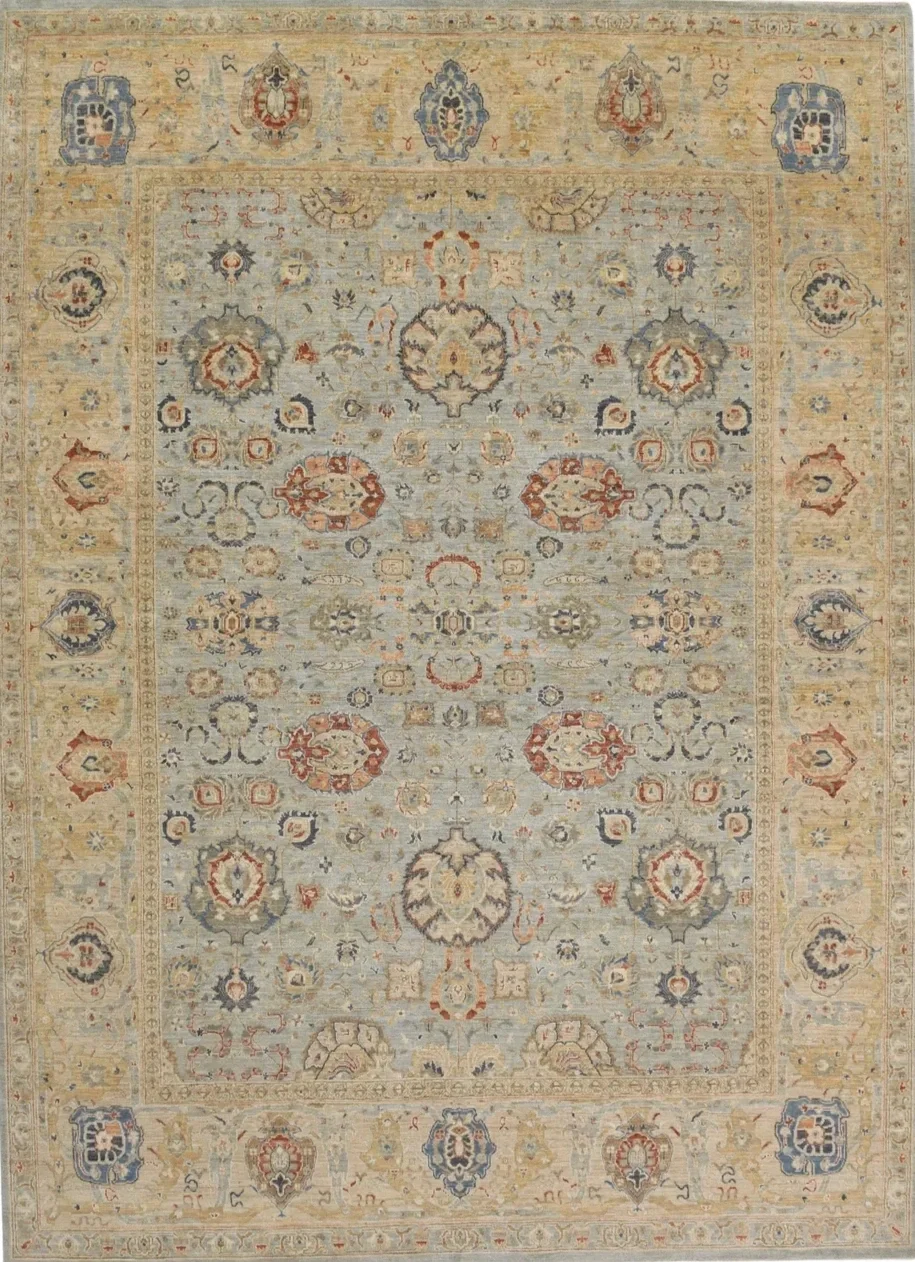 An ornate traditional area rug with a beige border and light blue interior, featuring symmetrical floral and geometric patterns in red, blue, gray, and beige.