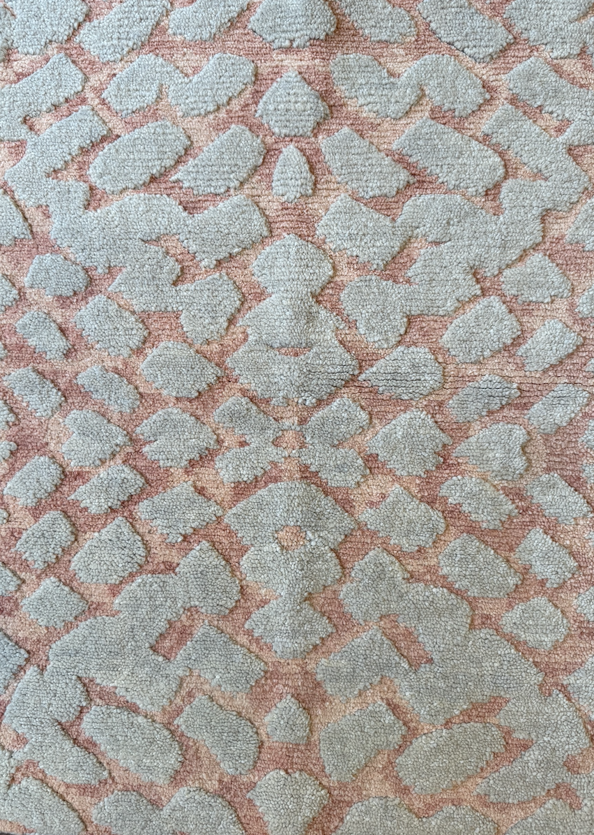 Close-up of a patterned carpet with a design resembling a giraffe's spots in beige and tan colors.