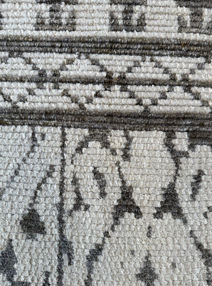Close-up of a patterned area rug with geometric designs in shades of gray and black.