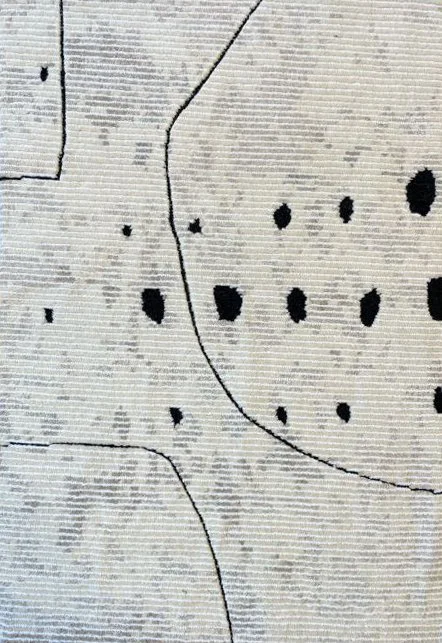 Close-up image of a white rug with black dots and lines.