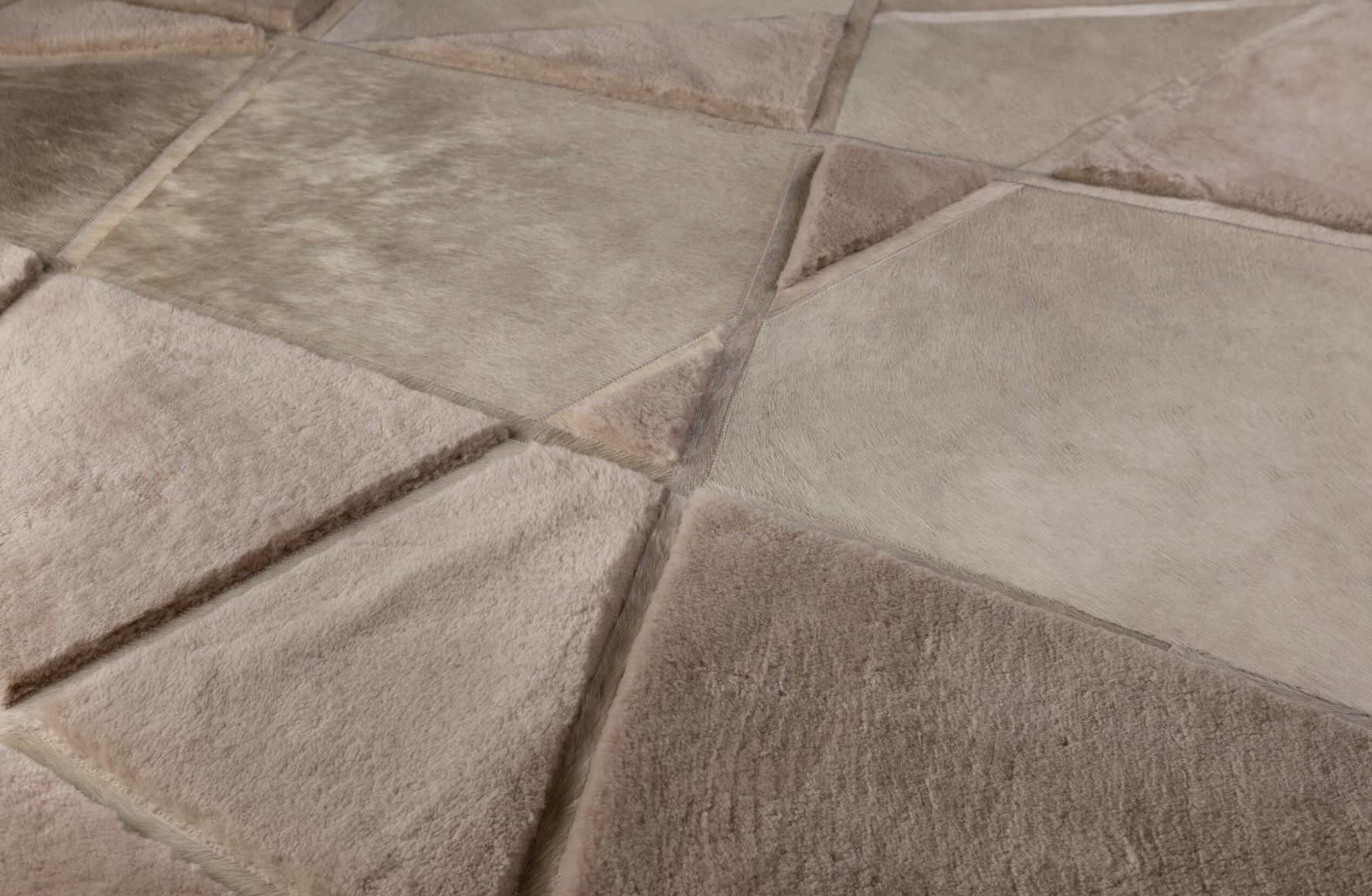 Close-up of a patterned tiled floor with a mix of beige, brown, and cream-colored tiles, some with a fur-like texture.