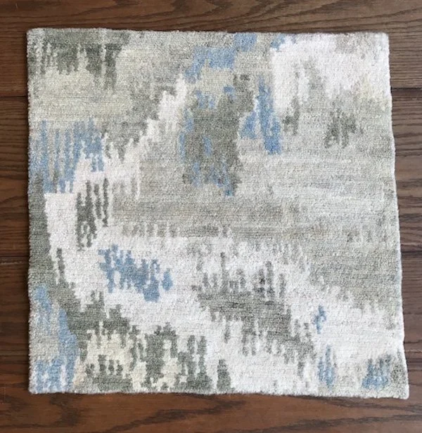 A beige and gray area rug with blue accents, placed on a wooden floor.