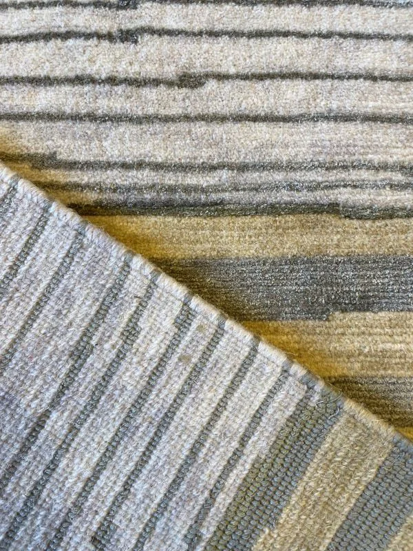Close-up image of the front and back of a cream, yellow, and green rug with a linear horizontal pattern.