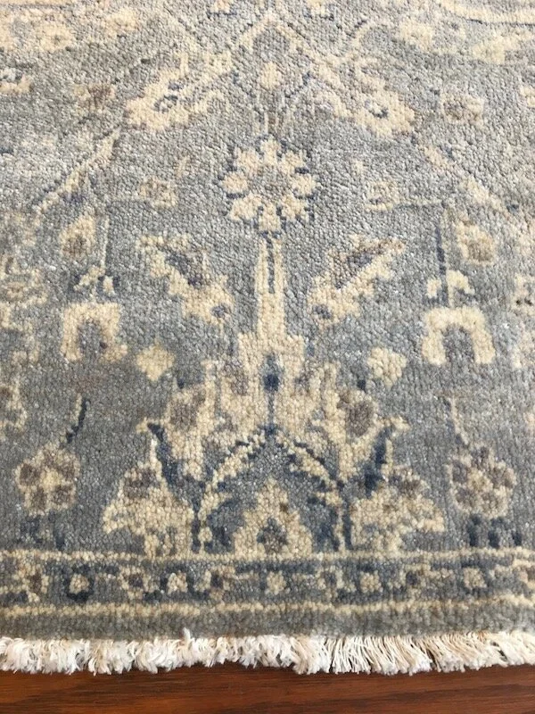Close-up of a decorative area rug with a floral and geometric pattern in neutral tones.