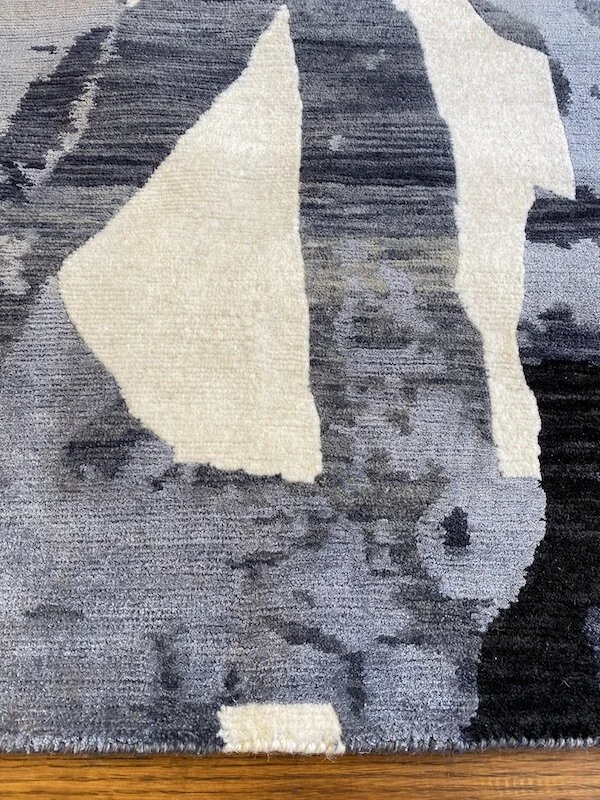 Close-up of a patterned area rug with shades of black, gray, and cream, featuring abstract shapes and designs.