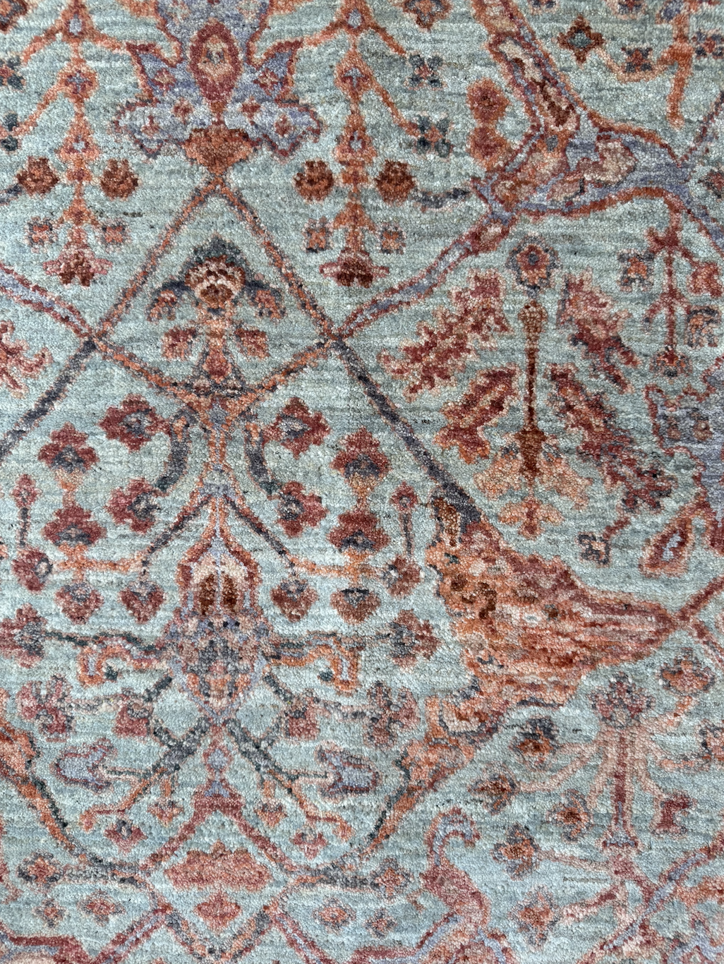 Close-up of a patterned area rug with floral and geometric designs in shades of red, orange, brown, and blue.