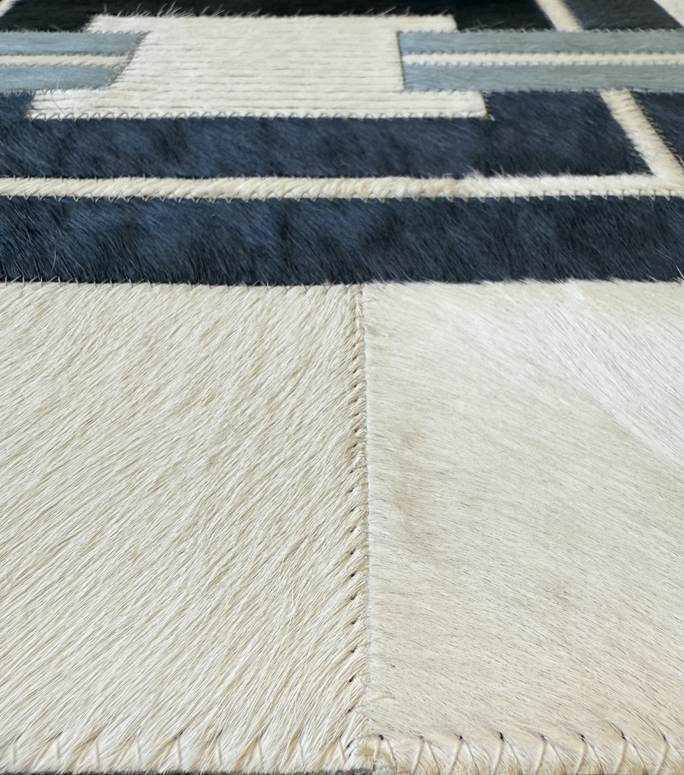 Close-up of a cowhide rug with a geometric pattern in black, white, and light beige colors.