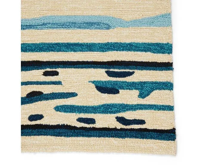 Close-up of a textured area rug with abstract blue, black, and beige stripes and spots.