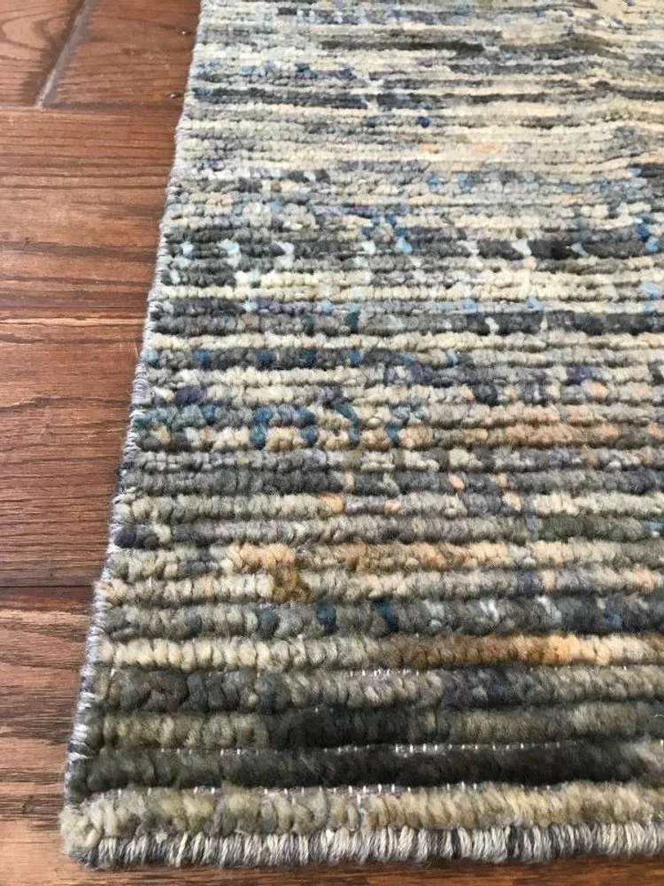 Close-up of a multicolored, textured rug on a hardwood floor.