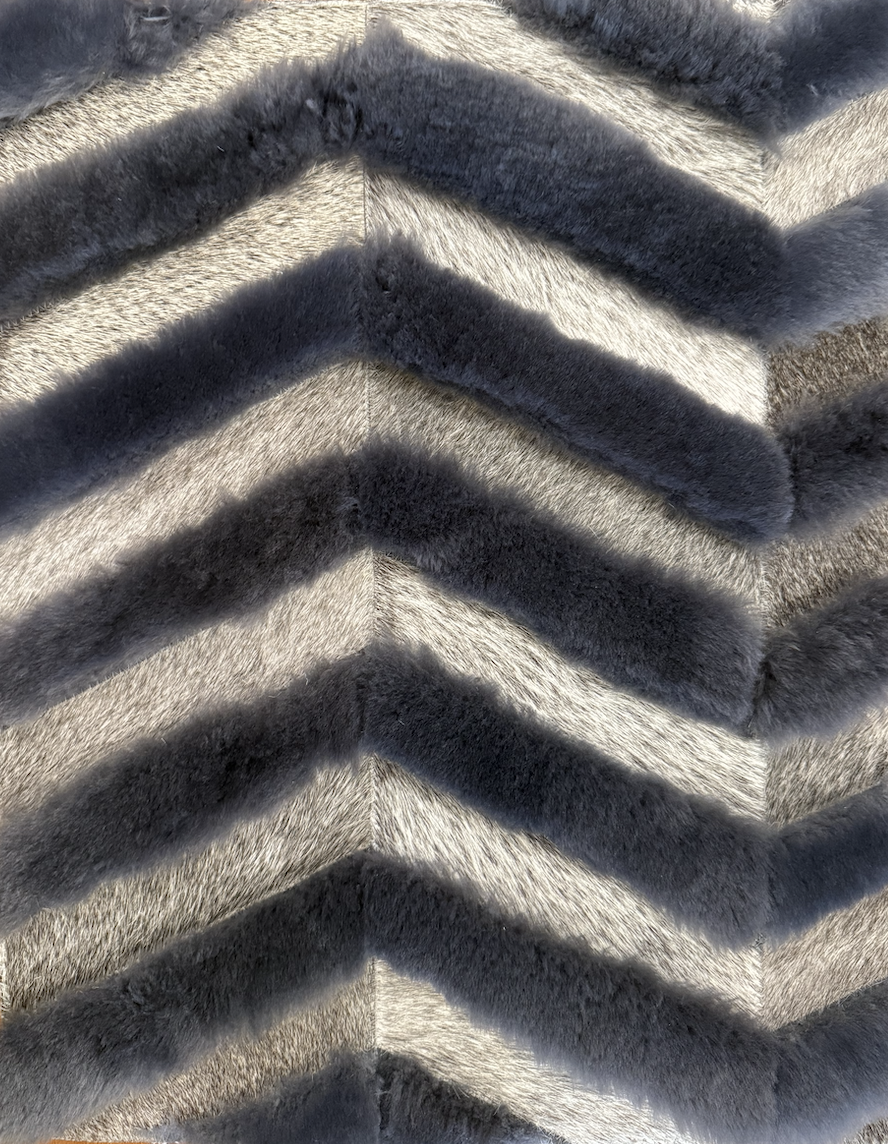Close-up of a chevron pattern made from strips of grey and black fur, arranged in a zigzag design.