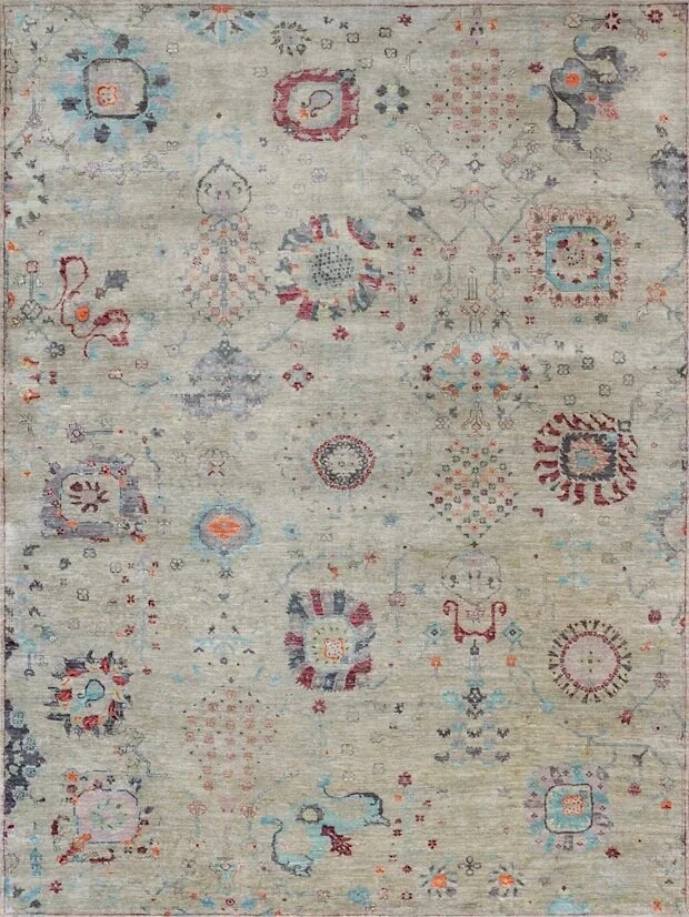 A vintage-style area rug with a beige background featuring various floral, geometric, and abstract patterns in red, blue, orange, black, and gray colors.