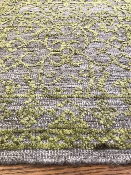 Close-up of a patterned gray and green area rug on a hardwood floor.