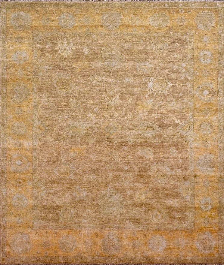 Old beige and light brown area rug with faded geometric border pattern.