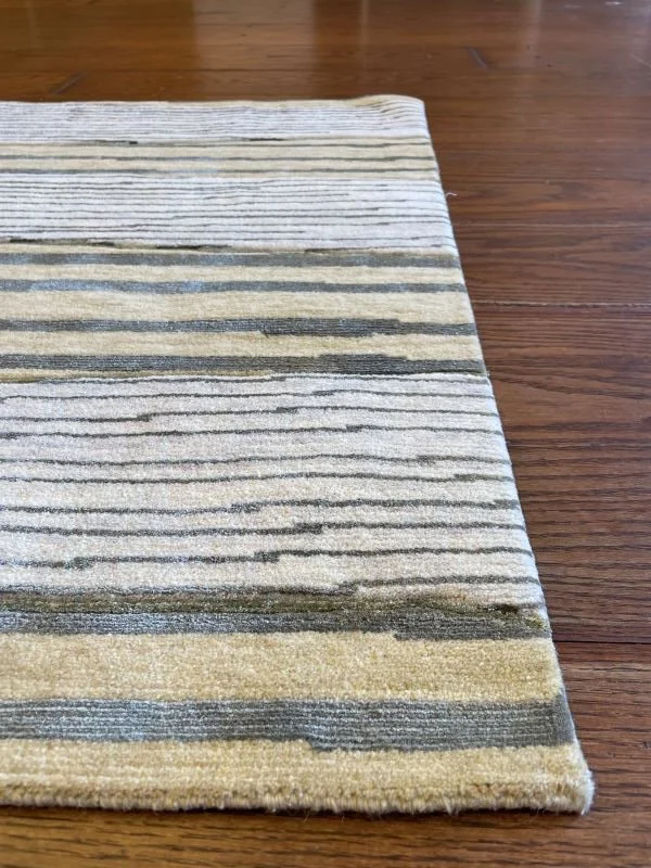 Close-up image of a cream, yellow, and green rug with a linear horizontal pattern.