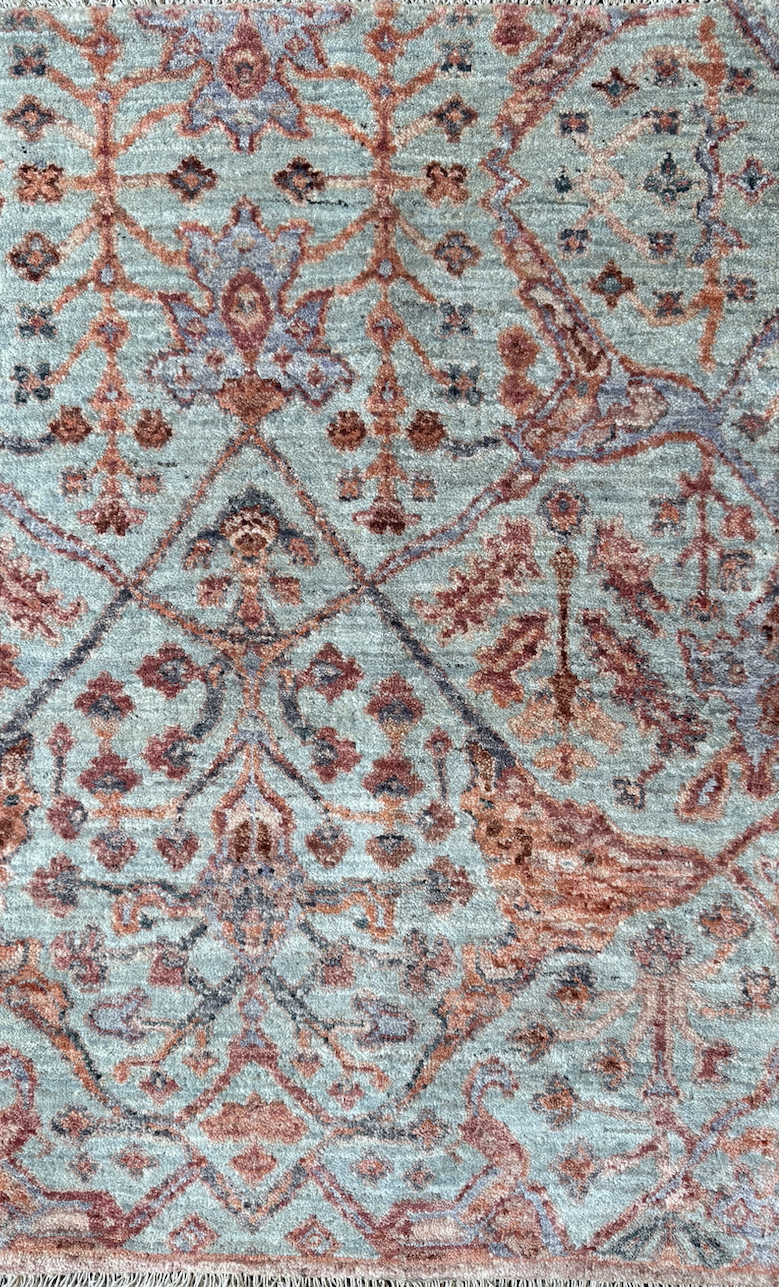 Close-up of a traditional patterned rug with floral and geometric designs in shades of blue, red, and beige.