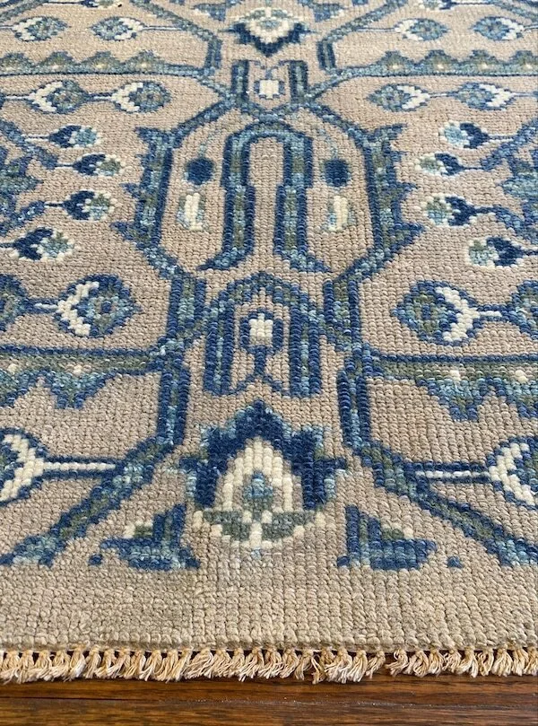 Close-up of a traditional woven rug with intricate blue and beige patterns.