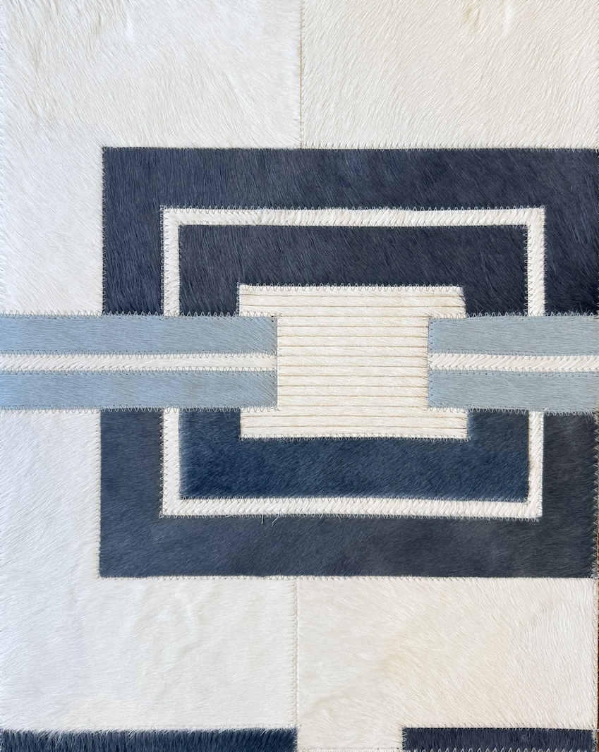 Geometric pattern made of fabric pieces in shades of white, black, and gray, stitched together with zigzag stitching.