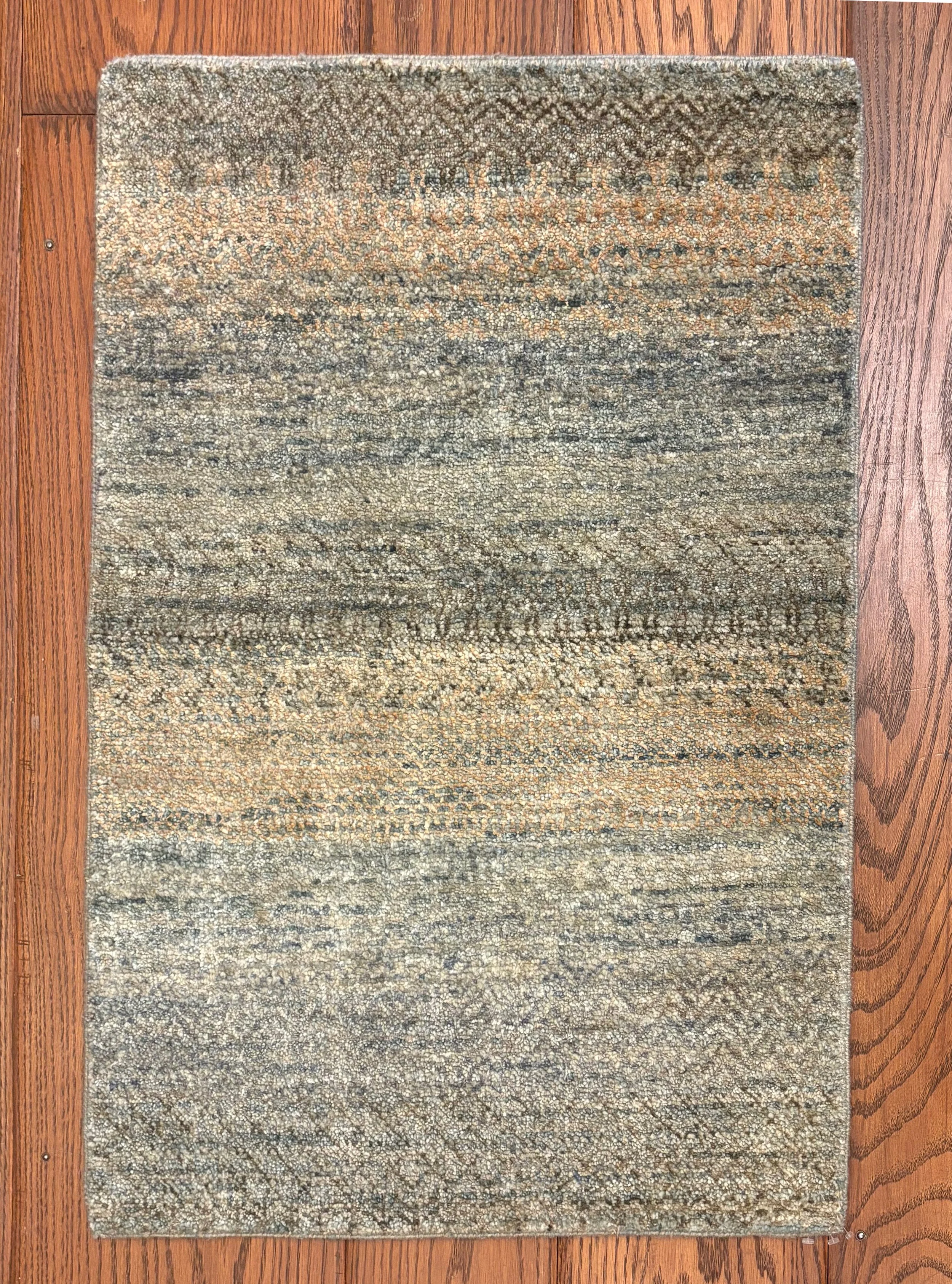 Colorful Persian-style rug with intricate patterns in shades of beige, gray, black, and orange, placed on a wooden floor.