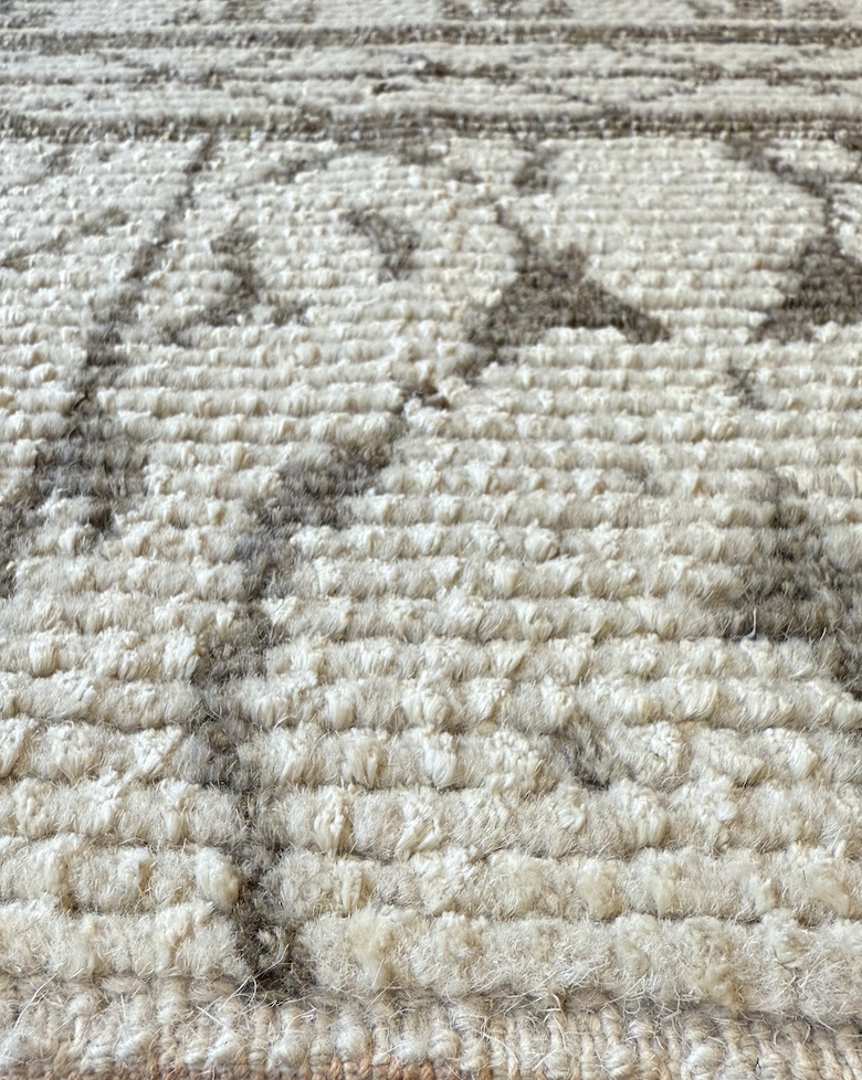 Close-up of a textured beige carpet with a partial drawing of a bunny and the letter 'H' in dark brown or black fibers.
