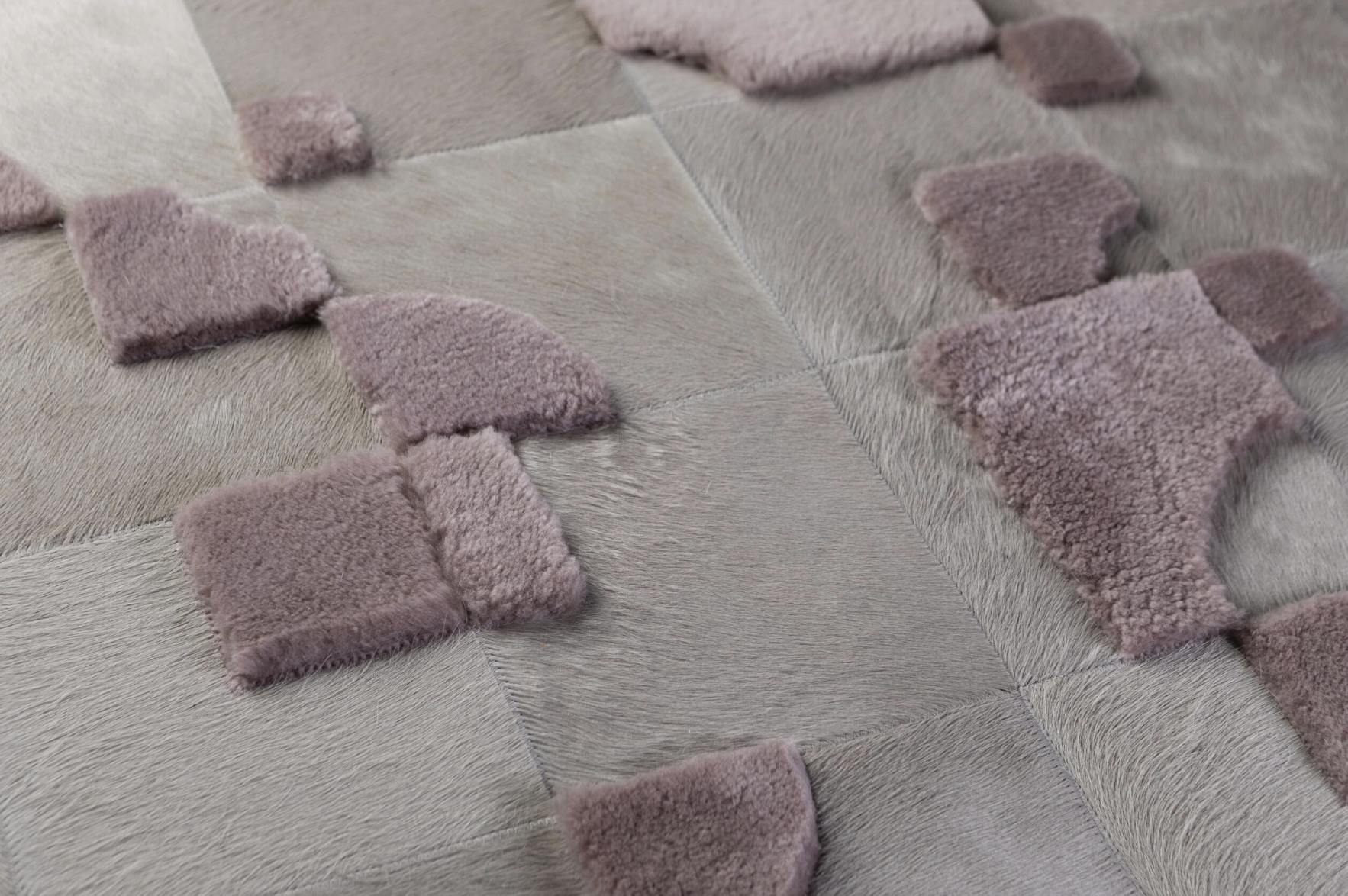 Close-up of a quilt or blanket with square patches of animal fur and plush pink fabric arranged in a geometric pattern.