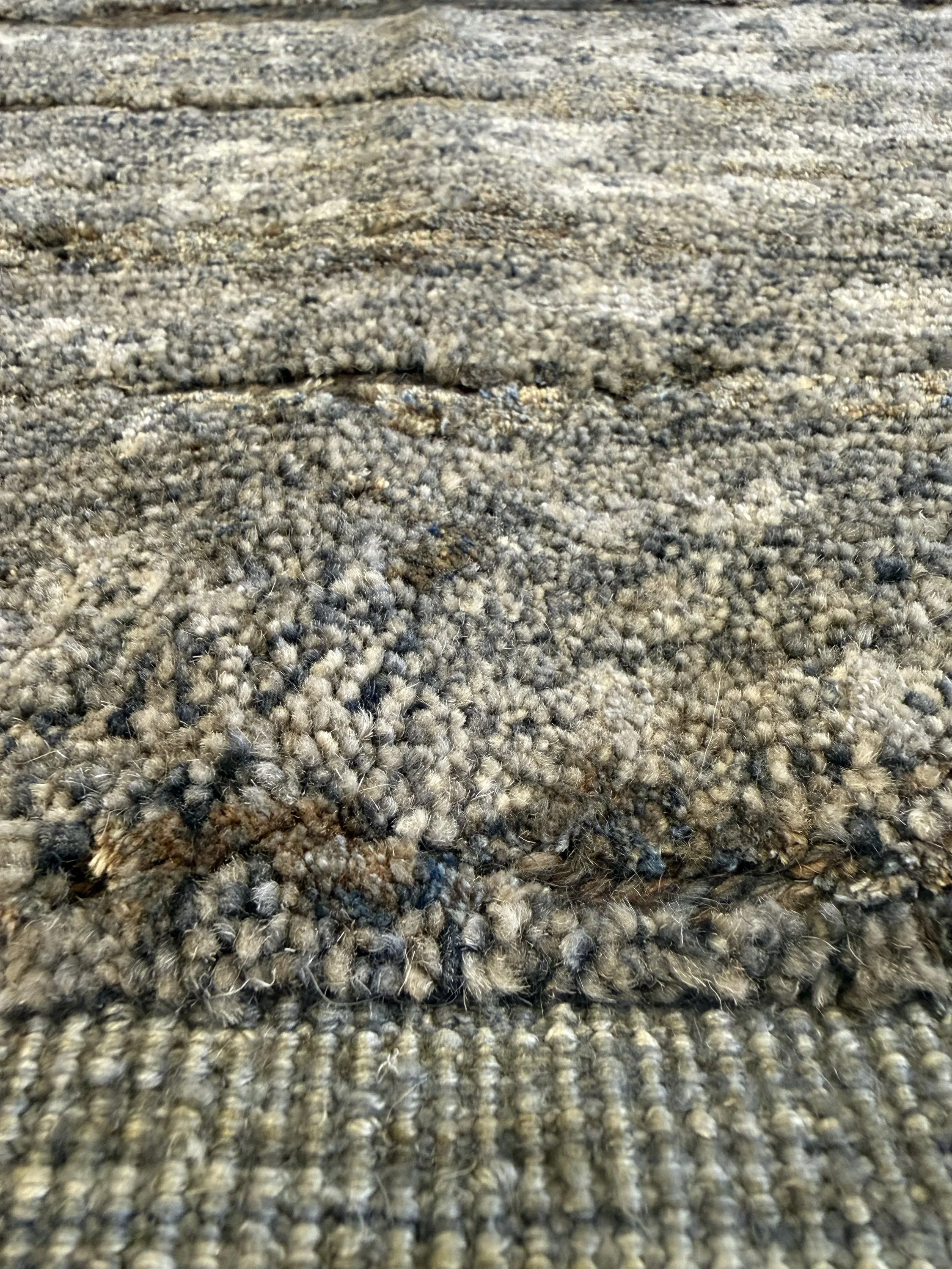 Close-up image of a wooden-textured rug in grey and brown tones.