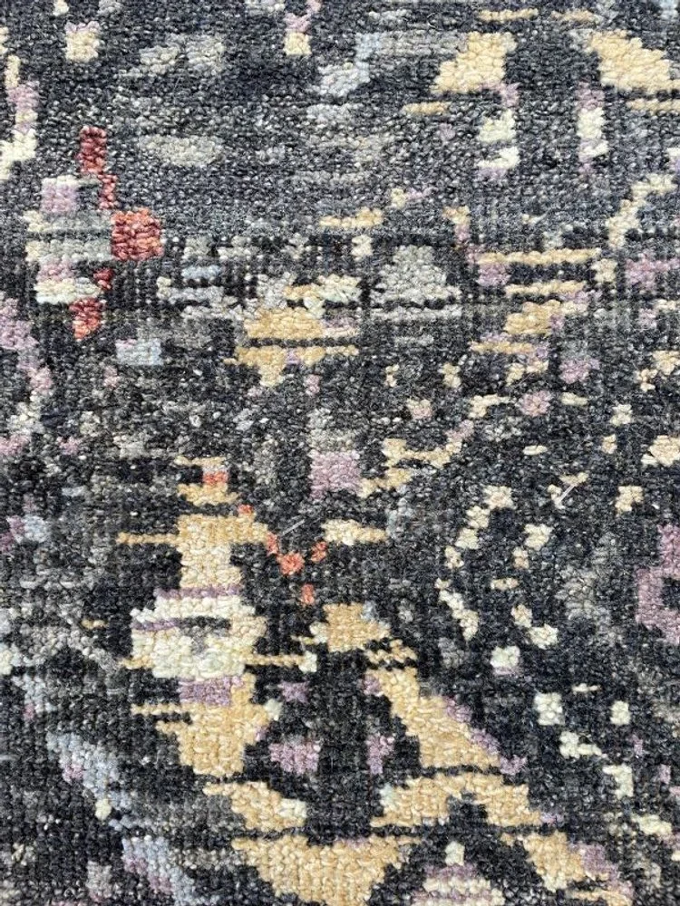 Close-up image of a textured, woven area rug with floral and geometric patterns in shades of black, beige, pink, and red.