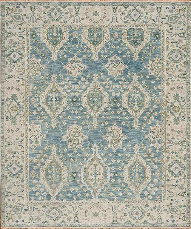 A traditional patterned area rug with a central design in shades of blue, cream, and light green.