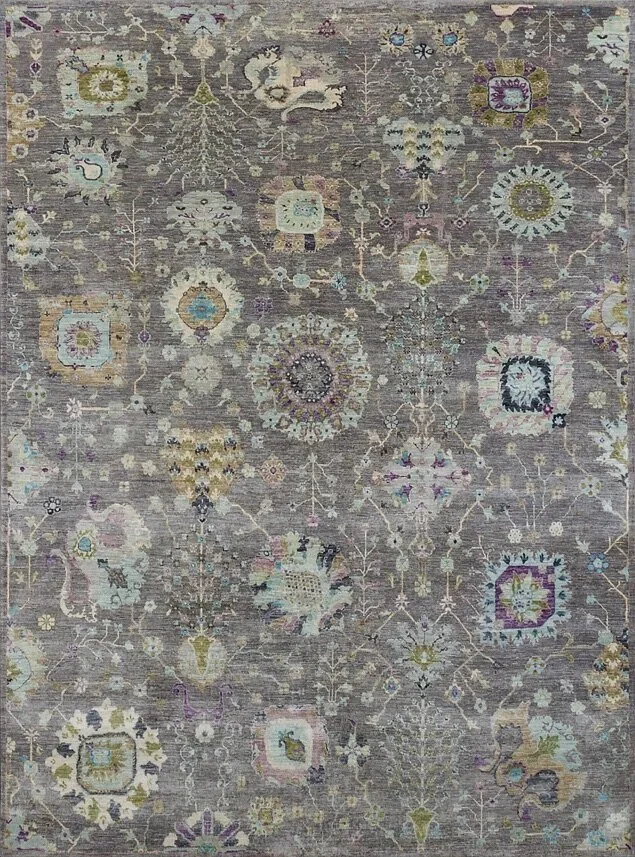 A detailed, vintage-style area rug with floral and geometric patterns in muted tones of gray, cream, blue, green, purple, and yellow.