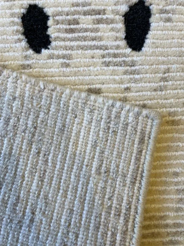 Close-up image of the front and back of a white rug with black dots and lines.