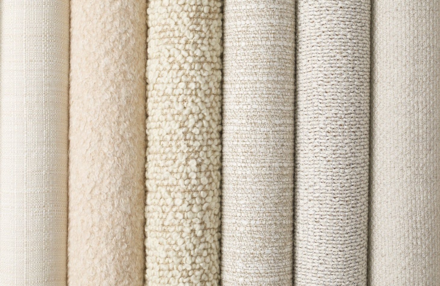 Cream-colored textured fabric rolls arranged vertically.