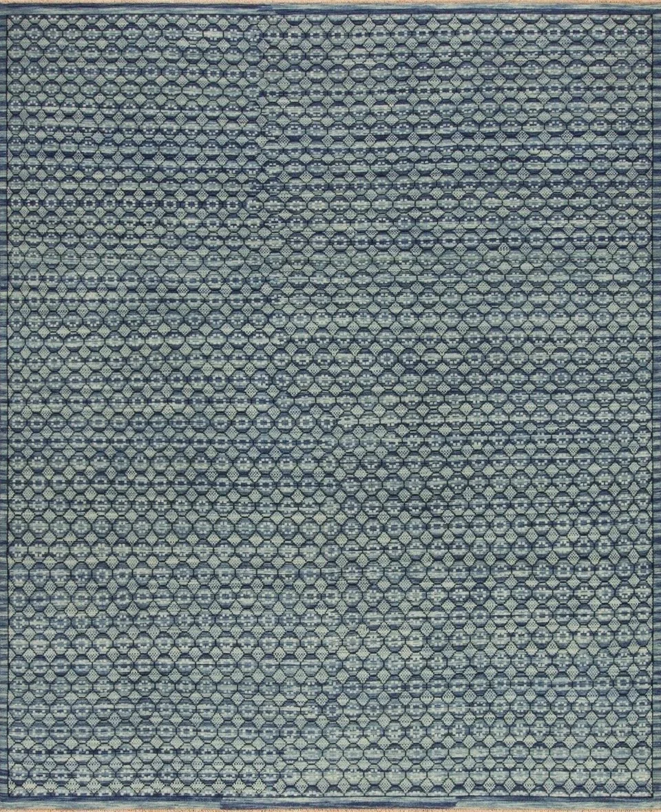 A patterned rug with a repetitive geometric design in shades of blue, gray, and cream.