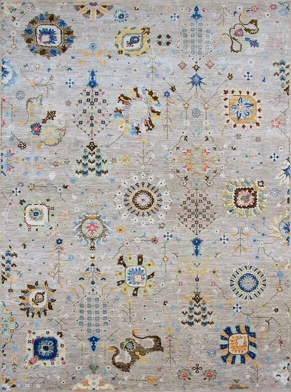 A detailed, ornate area rug with intricate patterns in shades of blue, beige, pink, and gold, featuring floral motifs and geometric shapes.