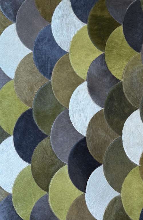 Close-up of a multicolored textured fabric with overlapping oval shapes in shades of green, blue, gray,white, and black.