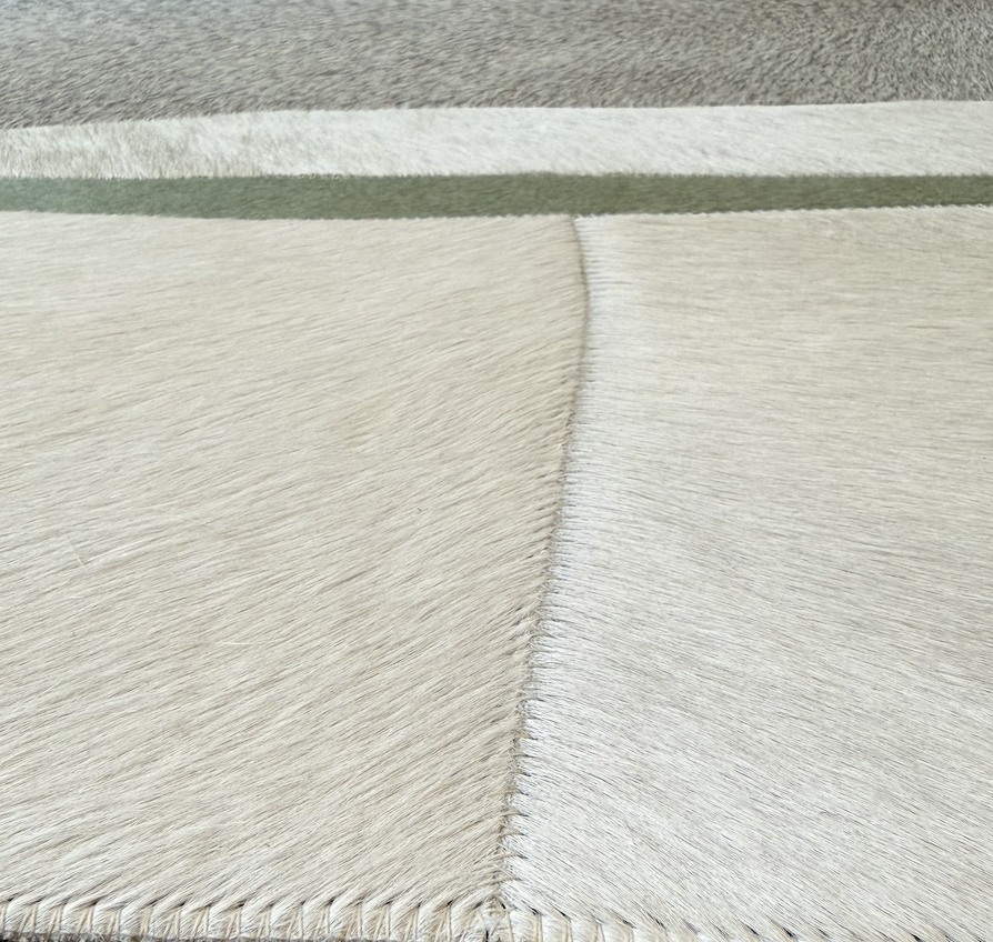 Close-up of the white fur of an animal, possibly a cow, with a stitched seam running vertically.