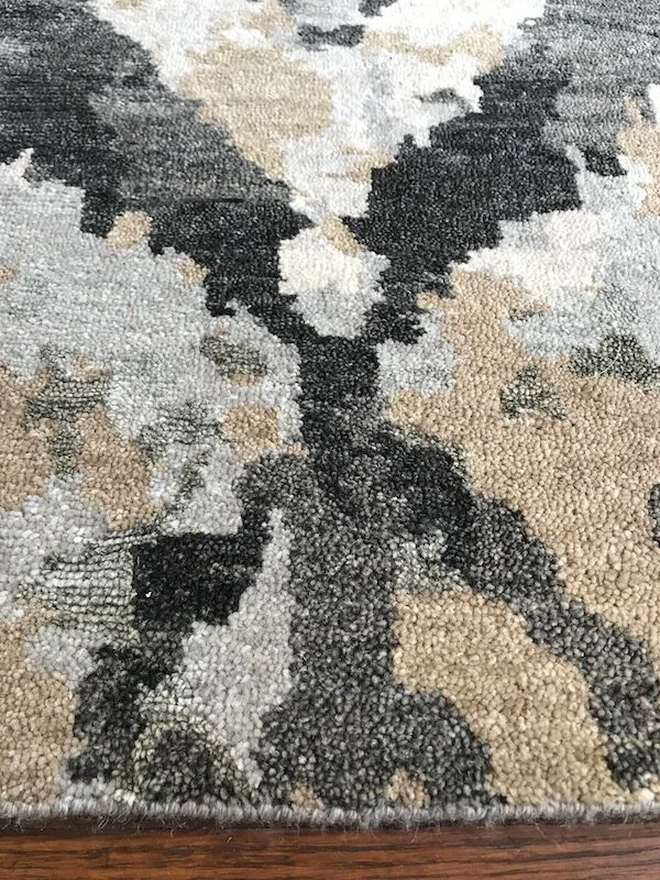 Close-up view of a patterned area rug with a design resembling a deer, featuring black and beige shades.