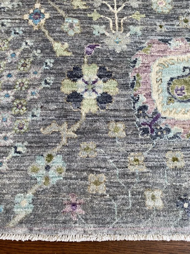 Close-up of a decorative area rug with floral and geometric patterns in pastel colors.