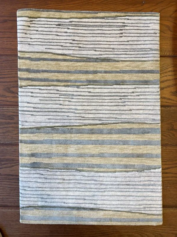 Close-up image of a cream, yellow, and green rug with a linear horizontal pattern.
