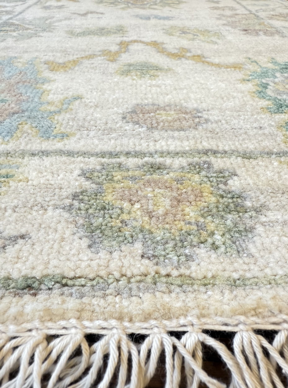Close-up of a decorative area rug with floral patterns and tassel fringe at the edge.