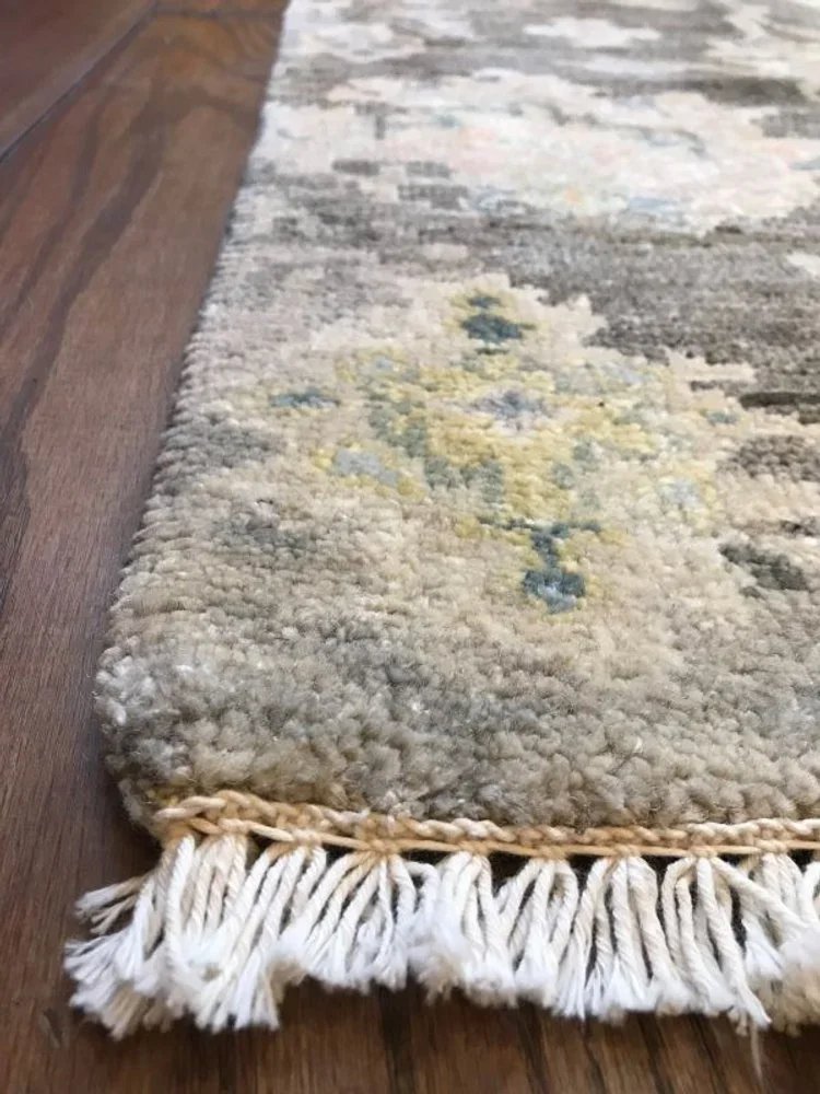 Close-up of a decorative area rug with tassels on a wooden floor.