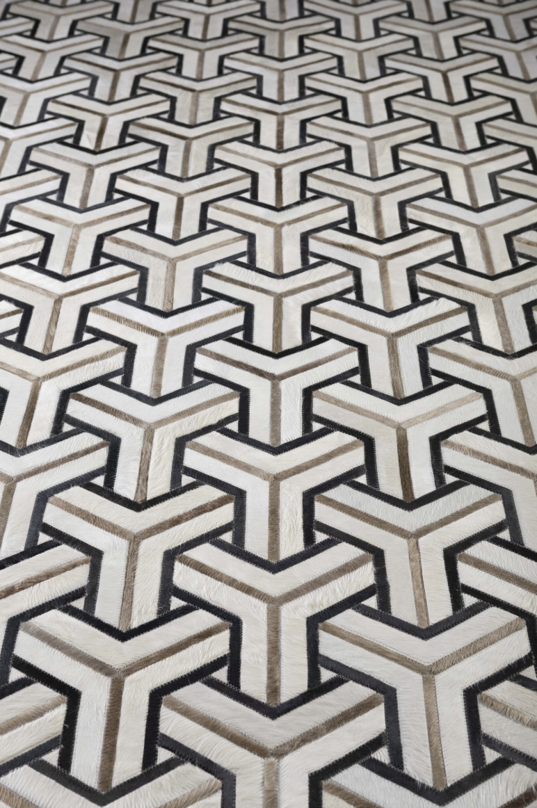 A geometric patterned carpet with repeating Y-shaped designs in black, beige, and white.