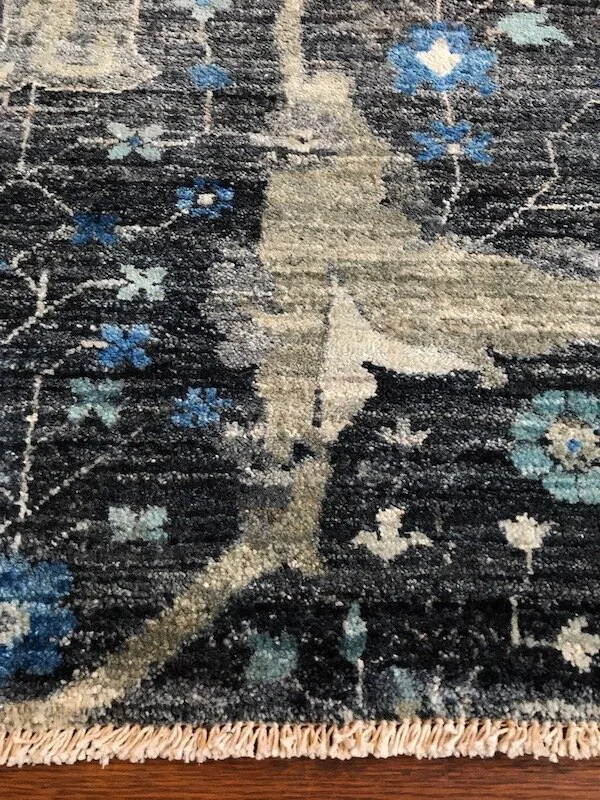 Close-up of a patterned rug with floral and leaf motifs in shades of blue, white, and beige.