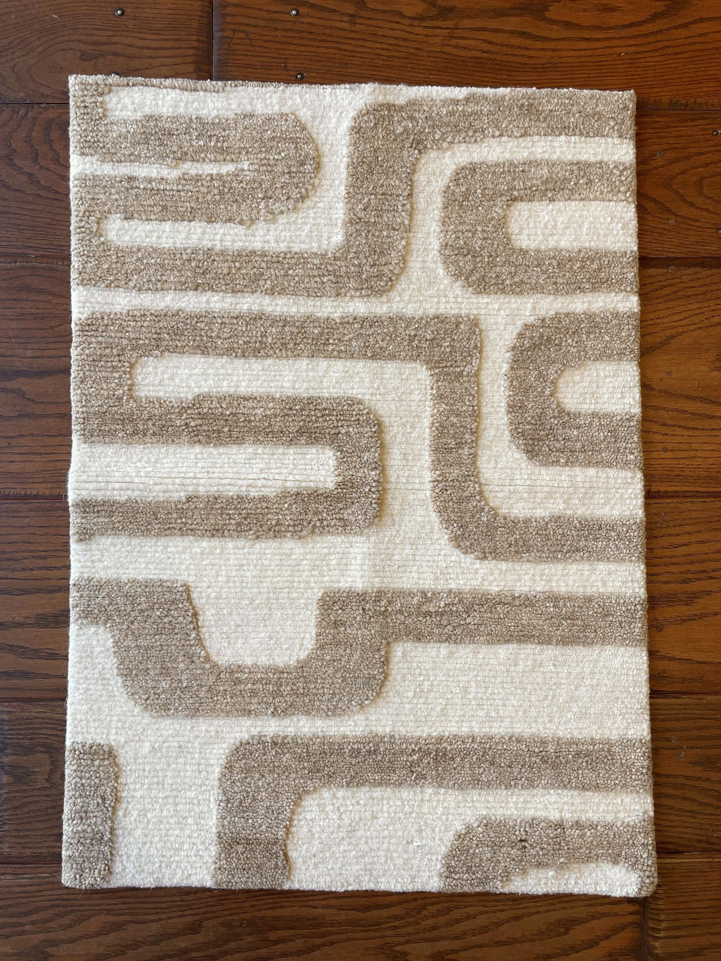 Beige and brown geometric patterned area rug on wooden floor.