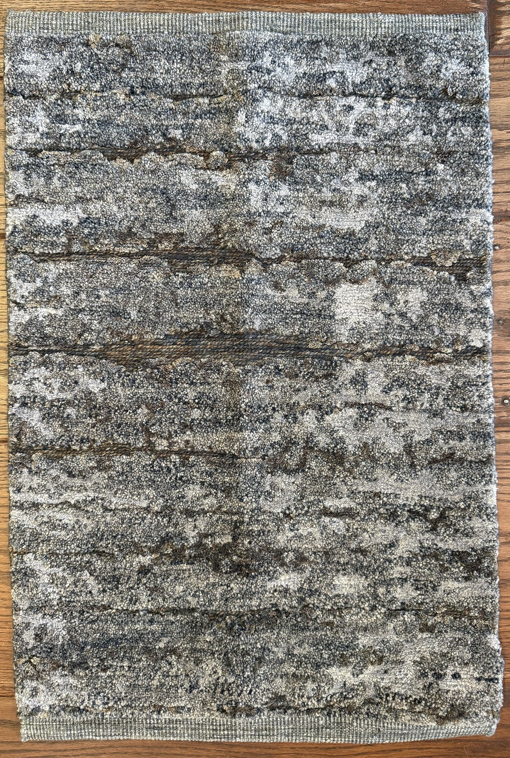 Close-up image of a wooden-textured rug in grey and brown tones.