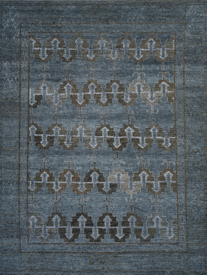 A blue patterned rug with a repeating geometric design in brown, beige, and light blue tones.