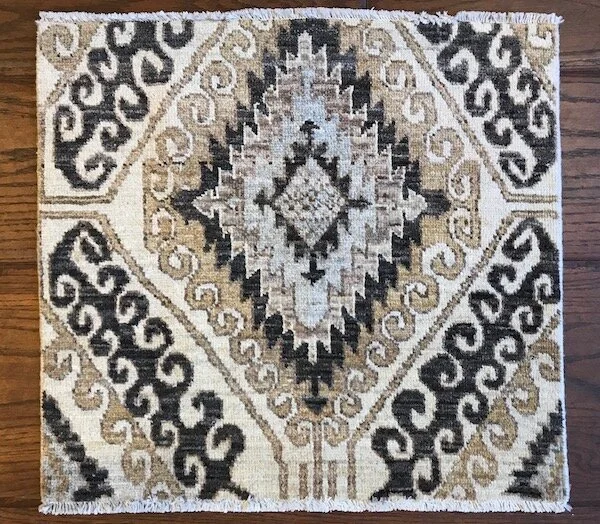 Decorative area rug with geometric black, beige, and gray patterns on a wooden floor.